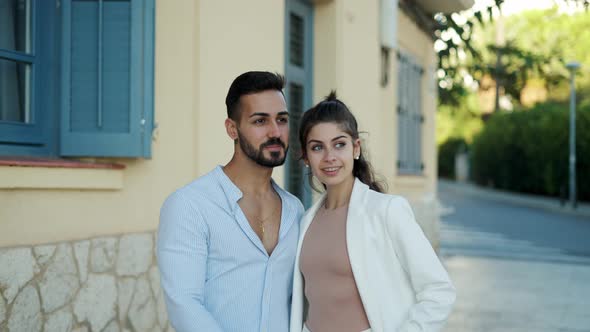 Smiling Hispanic Couple Holding Hands While Talking on Street