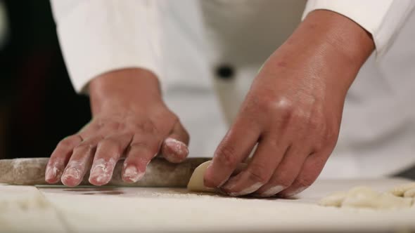 Hand rolling the edge of Chinese dumplings with a traditional wooden rolling pin