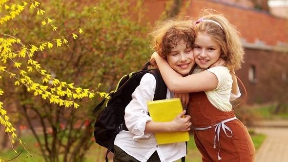 Schoolchildren, Brother and Sister, Boy and Girl Hug Against the Background of a Blossoming Spring