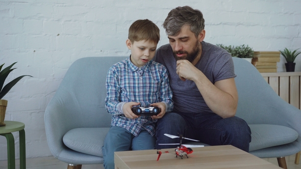 Cute Child Is Holding Transmitter and Controlling Flying Helicopter 