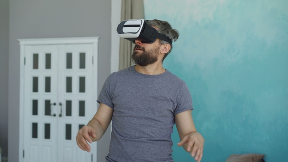 Bearded Man in Casual Clothes Is Using Virtual Reality Glasses and Gesturing While Standing