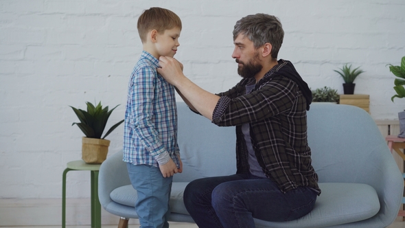 Careful Father Helping His Little Son to Get Dressed Buttoning His Shirt