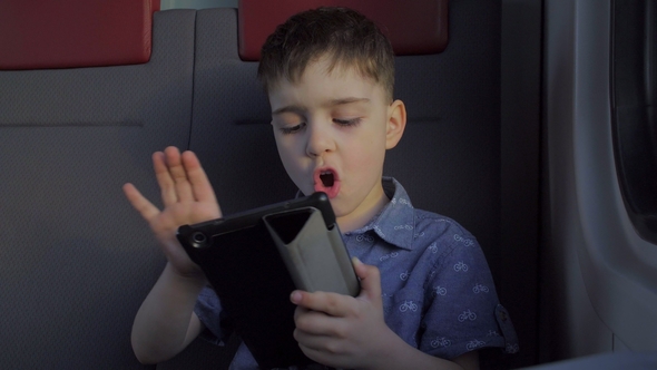 Boy Riding in the Train Playing Games on the Tablet