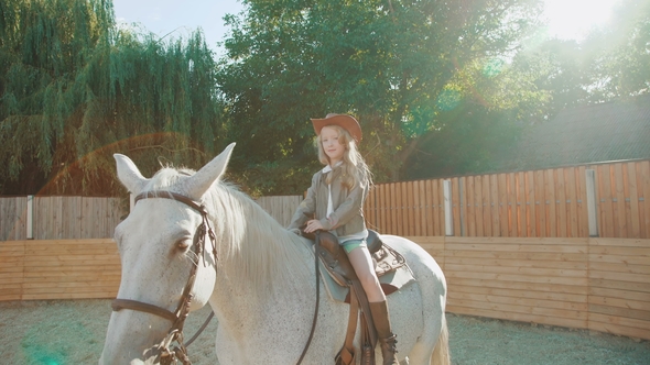 Pretty Girl Sitting on the Friendly Horse and Caresses It on Sunny Day