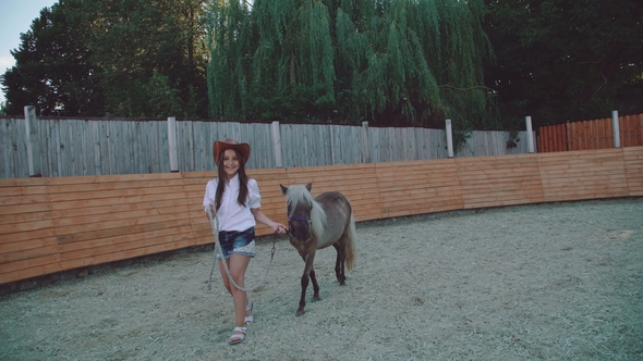 Pretty Girl Walks with a Beautiful Pony on the Arena