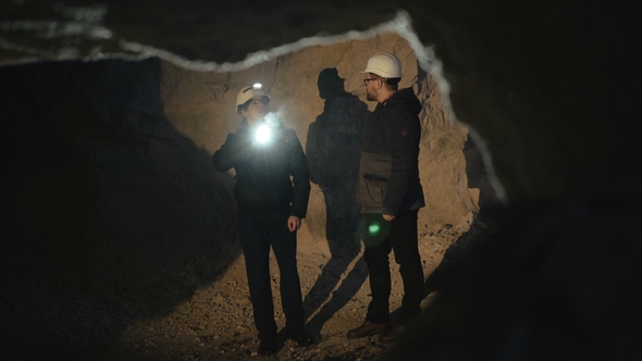 Two Speleologists with Flashlight Exploring the Cave with Fear in Darkness