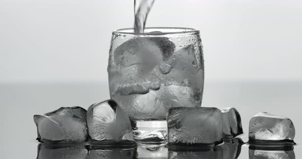 Pouring Up Shot of Vodka From a Bottle Into Glass. White Background