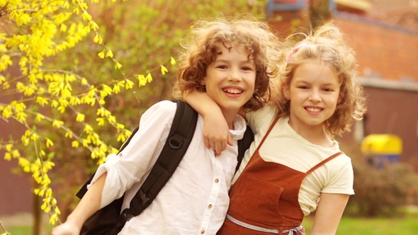 Schoolchildren Brother and Sister Hug against the Background of a Blossoming Spring