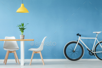e, a table with a plant on it and a yellow lamp above, against blue wall