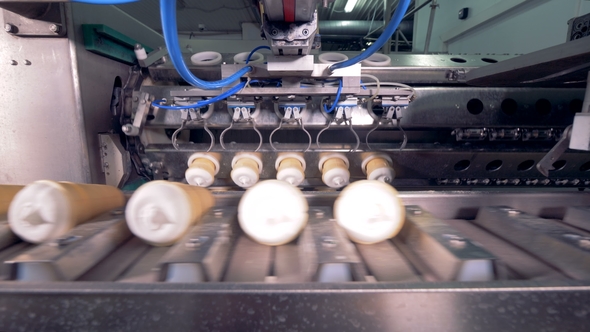 Automatic Metal Tongs Are Putting Batches of Waffle Ice-cream Onto the Conveyor Belt