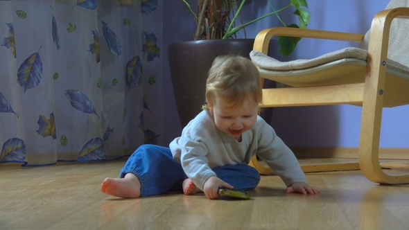Wonderful Blue-eyed Child Sits on the Floor and Talks on the Cell Phone