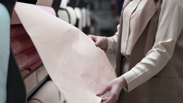 Female Hands Choose Wallpaper on Shelves in a Construction Supermarket, Close-up