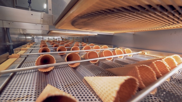 Horizontal Rows of Empty Wafer Cones Are Moving Along Metal Ducts