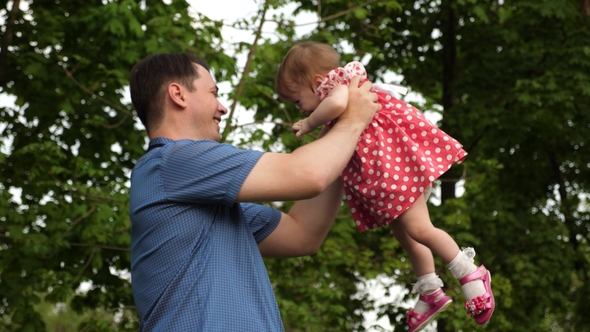 Happy Dad Turns His Daughter on His Hands Walk with Her in the Green Park