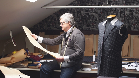 Mature Tailor Working with Cut Patterns at Workshop in Late Evening.