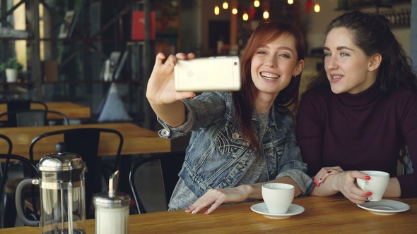 Pretty Girls Best Friends Are Taking Selfie with Smartphone Then Watching Photos While Drinking