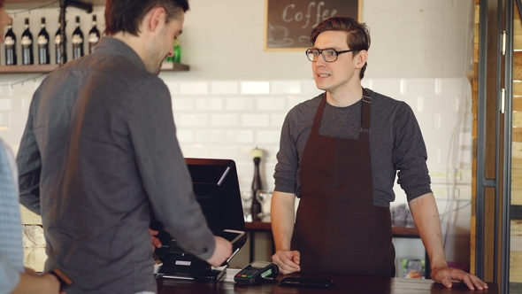 Friendly Barista Handsome Man Is Selling Takeout Coffee and Accepting Contactless Mobile Payment