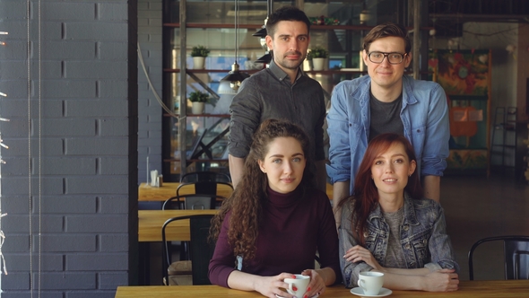 Portrait of Two Happy Couples in Casual Clothing in Modern Cafe with Tea Cups