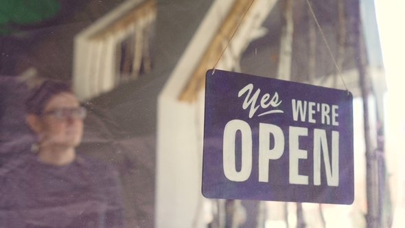 Handsome Male Cafe Worker in Apron Changing Doorplate from "Yes We Are Open"