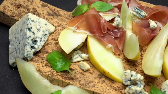 Sliced Prosciutto and Melon on a Cork Wooden Board