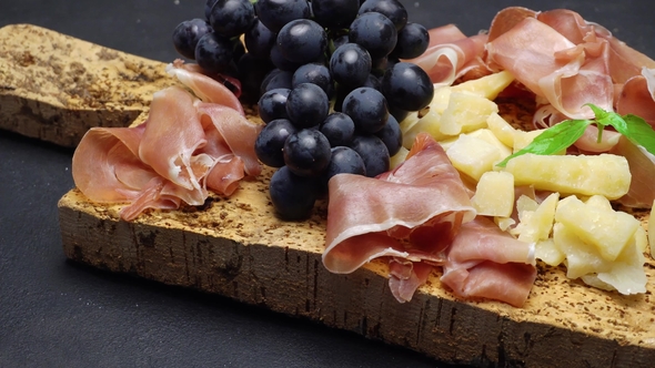 Sliced Prosciutto or Jamon Meat and Cheese on Cork Wooden Board