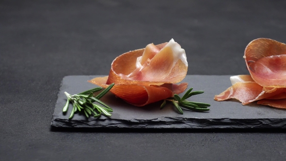 Sliced Prosciutto or Jamon Meat on Dark Concrete Background