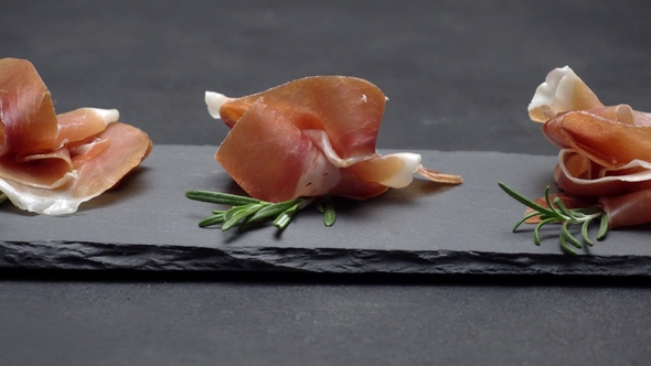 Sliced Prosciutto or Jamon Meat on Dark Concrete Background