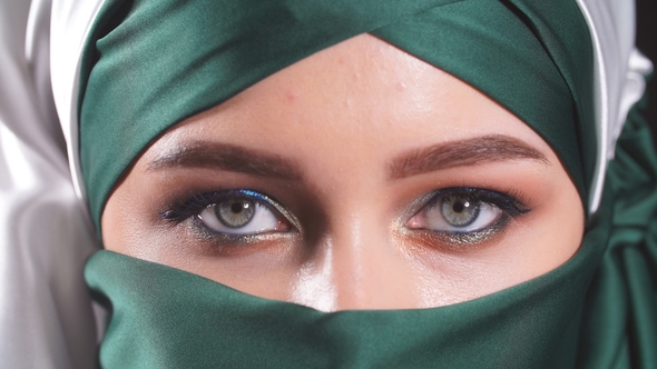 Beautiful Asian Muslim Woman with Niqab Traditional Veil Isolated Over Black Background.