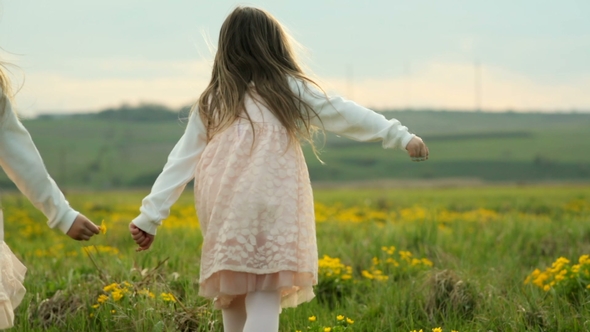 Two Little Girls Running Through the Green Meadow