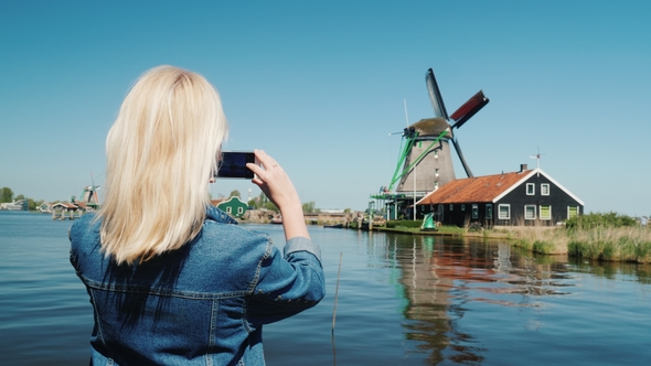 A Woman Tourist Takes Pictures of Old Windmills in Holland. Travel and Tourism in Europe