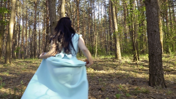 Elegance Girl in Blue Dress Walks in Forest