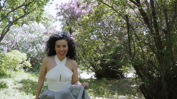 Beautiful Laughing Brunette Runs on Camera Through a Summer Garden