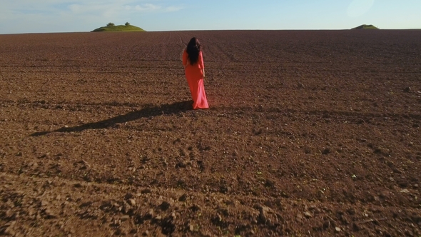 Girl in Long Red Dress Walk Through Plowed Field