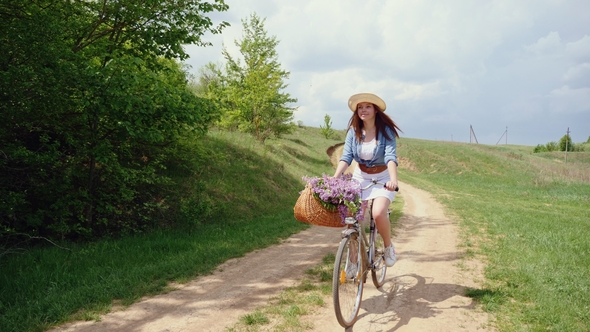 Woman in a Hat on a Bicycle Traveling in Nature