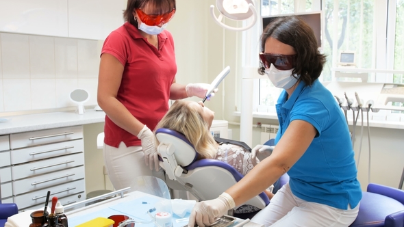 Dentist and Assistant Treating Patient's Teeth with Curing Photopolymer