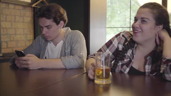 Plump Girl Drinking Beer with Friends Sitting at the Table in the Bar