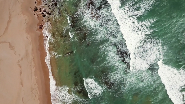 Aerial Tilt View on Ocean Waves, Beach and Rocks