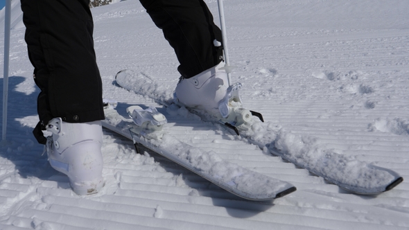 Woman Skier Unfastens Mountain Ski Boots Using Sticks