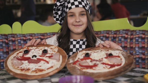 The Young Girl Shows Two Pizzas at Camera.