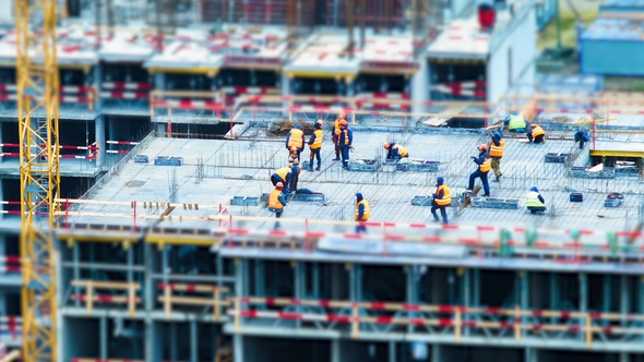 Builders and Cranes Working on the Construction Site