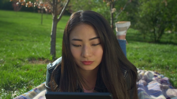 Charming Asian Girl with Tablet Pc in Spring Park