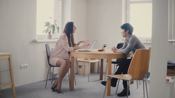 Confident European Female Lawyer Talking To Young Japanese Man By the Table. Multiethnic Discussion