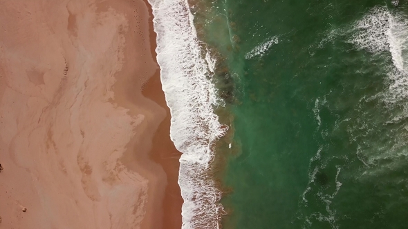 Aerial Tilt View on Ocean Waves and Sand Beach