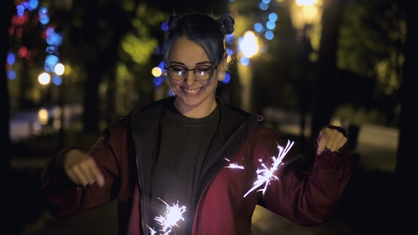 Portrait of Hipster Girl with Blue Dyed Hair Looks with Sparklers in Their Hands. . Beautiful Young