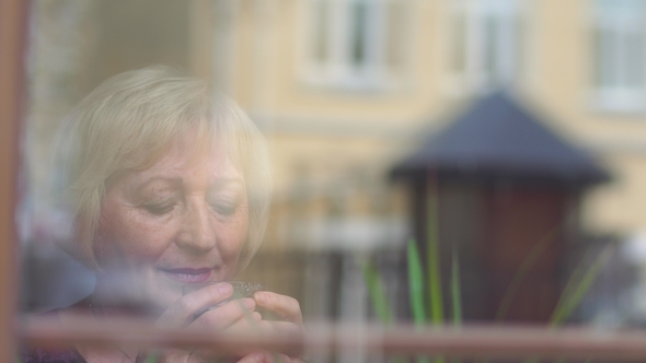 Beautiful Mature Woman Drinking Coffee near the Window