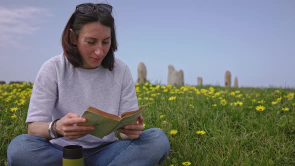 A Girl Reads a Book Sitting on the Green Grass