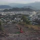 Woman Does Yoga in Lotus Pose Against City Near Mountains - VideoHive Item for Sale