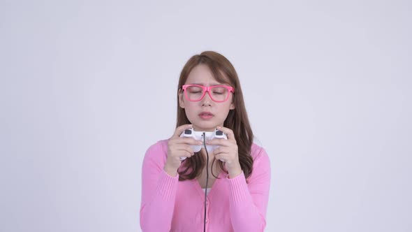 Face of Young Focused Asian Nerd Woman Playing Games