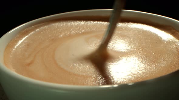Side View From Above of a Mug with Coffee the Hand of a Person Stirs the Foamy Foam Stirring the