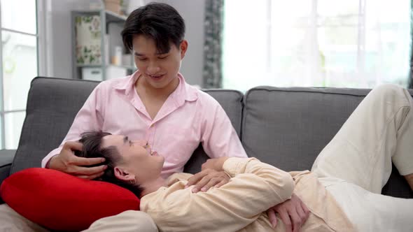 Asian young gay man couple lying on boyfriend's lap in house. 